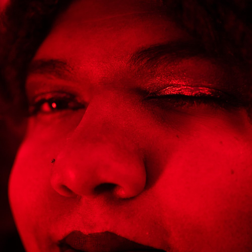 A closeup photo of Calicoma. It shows one closed eye in monochrome red light.